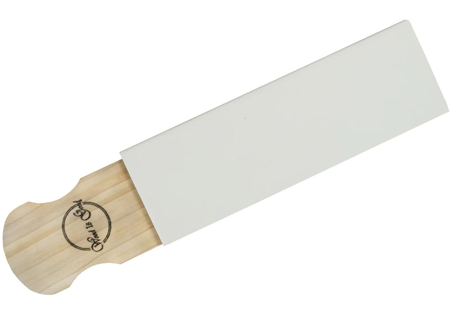 The Wood is Good Hone Strop by MID, perfect for refining your strop skills, is seen partially emerging from its white rectangular cover with a logo adorning the handle.