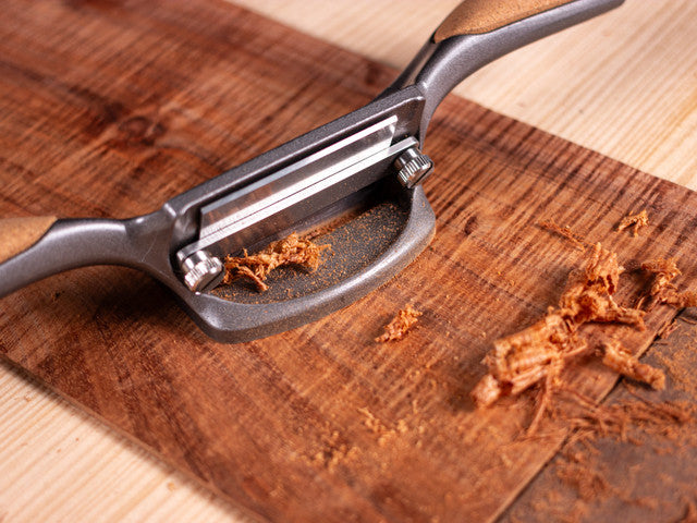 The Melbourne Tool Company's Cabinet Scraper expertly smooths a wooden board, leaving fine shavings behind.