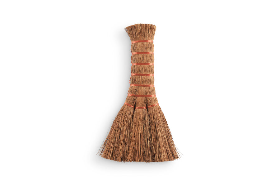 The MARU Japanese Natural Bristle Hand Broom, with natural straw bristles and vivid orange binding, is elegantly displayed against a plain white background.