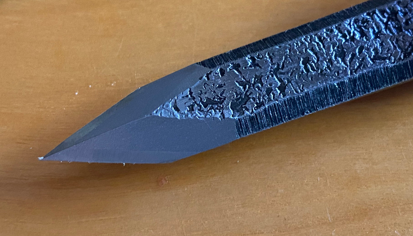 A close-up of a sharpened pencil tip on a wooden surface, evoking the precision and craftsmanship of the MARU Ikeuti Japanese Marking Knife with its double bevel edge, highlighting its detailed texture and graphite core.