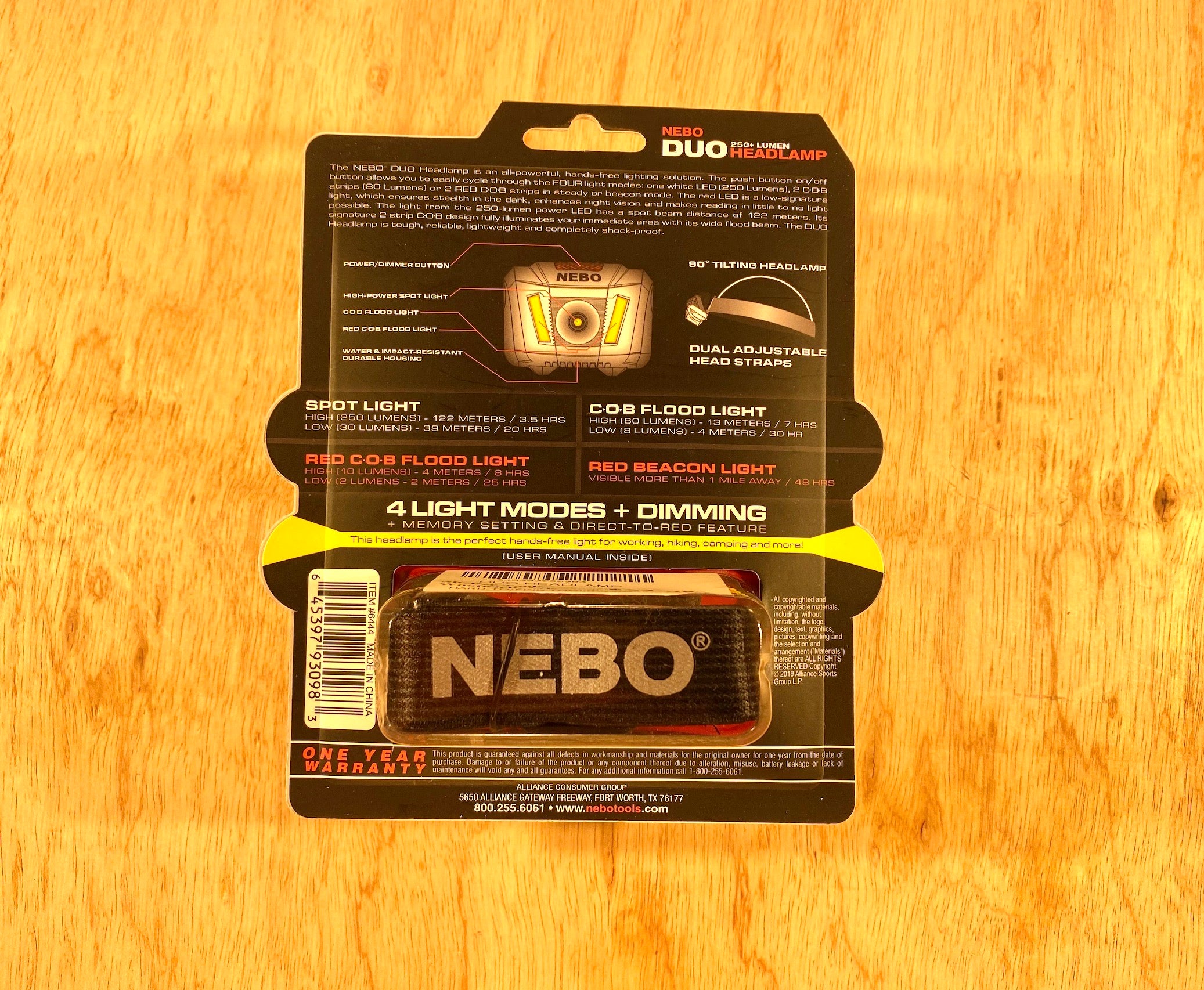 Packaging for the NEB Nebo Duo Headlight highlights four light modes, dual adjustable LED headlamps, and a one-year warranty. Providing 250 lumens of hands-free illumination, the packaging is set against a rustic wooden backdrop.